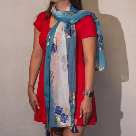 A light blue and white summer scarf with sea blue and gold embroidered aqua fish patterns and tassels at the ends