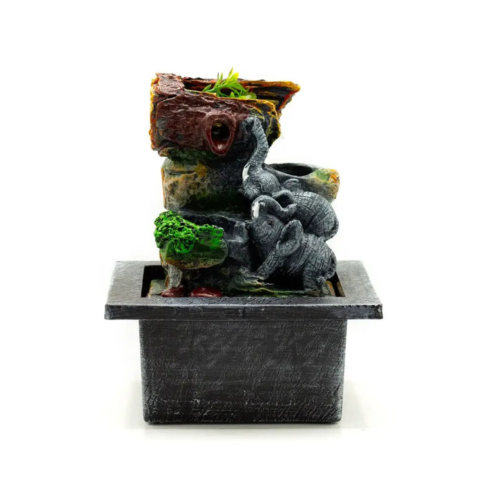 A 20cm tabletop water feature with flowing water, textured rock tiers, gray elephant sculptures, and green moss accents