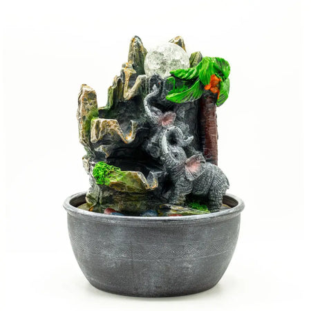 Gray resin tabletop water feature with a jungle scene of elephants, palm trees, and a moonstone centerpiece