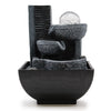 Black resin tabletop water feature with textured stone tiers and clear glass orb showing cascading water flow