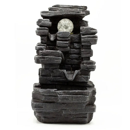 Black faux stone tabletop water feature with slab rocks formation and a clear textured crystal ball orb at center