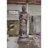 Bronze-colored antique gold standing buddha statue with intricate robes on a lotus base in an indoor workshop setting