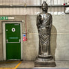 Tall antique gold standing buddha statue made of metal with intricate drapery and serene expression on ornate pedestal