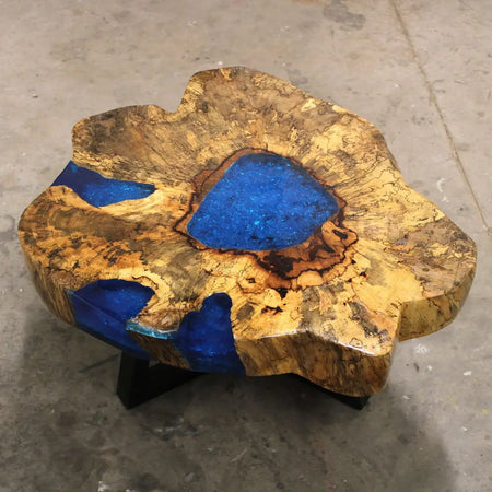 A rustic tamarind wood coffee table with natural golden-brown grain and bold sky blue resin inlays