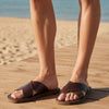 The Window, Milford Haven dark brown handmade leather sandals with crossed straps worn on a wooden beach boardwalk