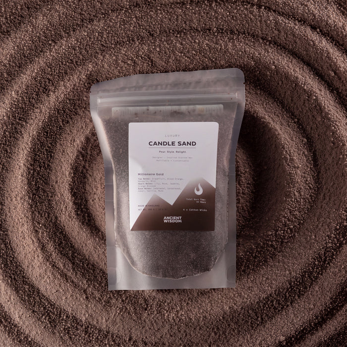 The Window, Milford Haven Millionaire Gold chocolate brown candle sand in a pouch set against a textured sand spiral.