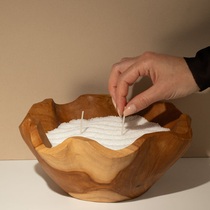 The Window, Milford Haven Cobalt candle sand in a rustic wooden bowl with a hand placing a cotton wick