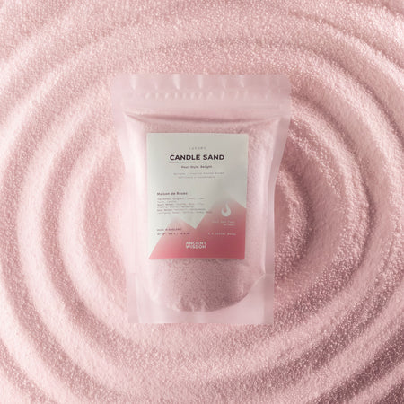 The Window, Milford Haven dusty rose scented candle sand in a pouch, surrounded by a swirl of loose pink wax beads.
