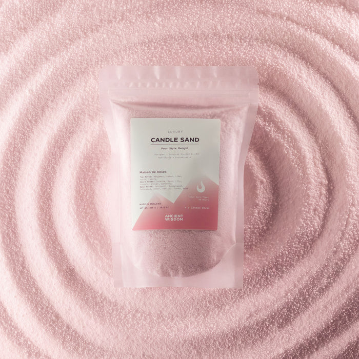 The Window, Milford Haven dusty rose scented candle sand in a pouch, surrounded by a swirl of loose pink wax beads.