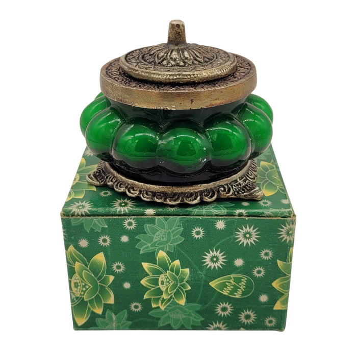 The Window, Milford Haven Song Of India green glass scented candle in an antique-style embossed metal jar on a box.