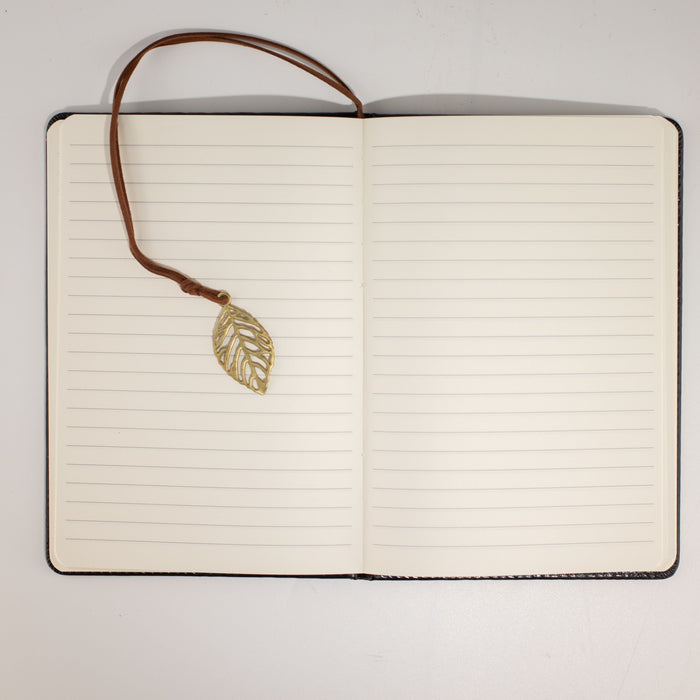 The Window, Milford Haven A5 notebook open to lined pages with a brass leaf bookmark on a leather-effect cover