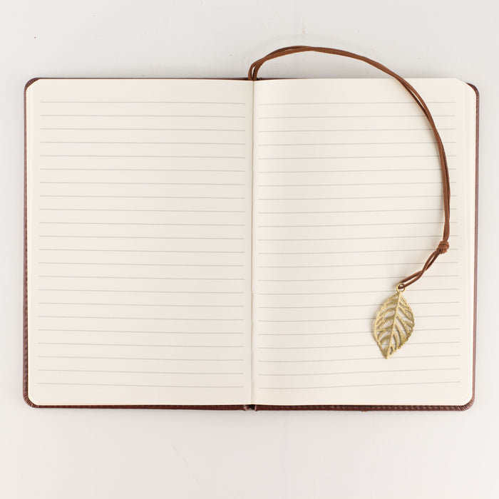 The Window, Milford Haven A5 notebook open to lined pages with a brass-coloured leaf bookmark on a brown leather cover