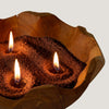 The Window, Milford Haven mocha brown Crimson Crystal candle sand burning with three wicks in a rustic wooden bowl.
