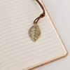 The Window, Milford Haven Doodlers Delight notebook featuring a brass-coloured leaf bookmark on lined paper pages.
