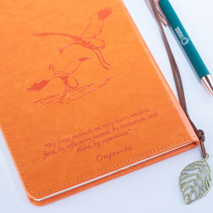The Window, Milford Haven orange leather-effect notebook with embossed water birds and a Confucius quote on the cover.
