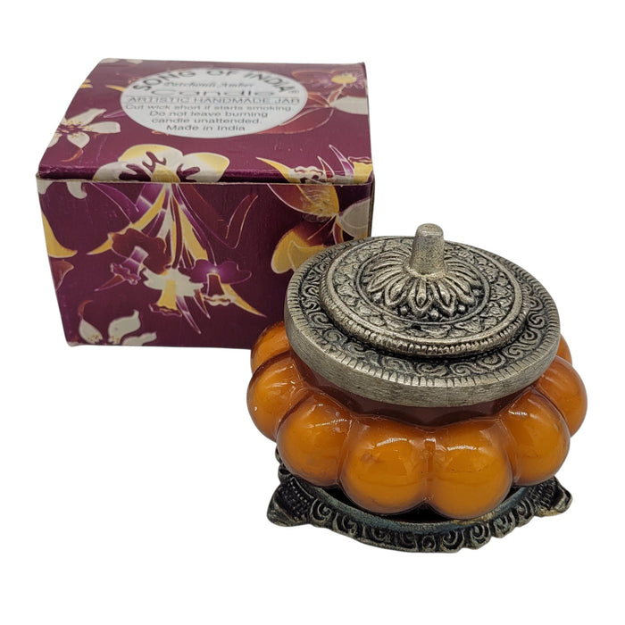 Song Of India Patchouli Amber scented soy candle in an orange pumpkin-shaped glass jar with ornate white metal lid.
