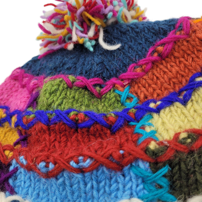 The Window, Milford Haven patchwork wool bobble hat featuring vibrant multi-coloured stitching and a wool pom-pom.