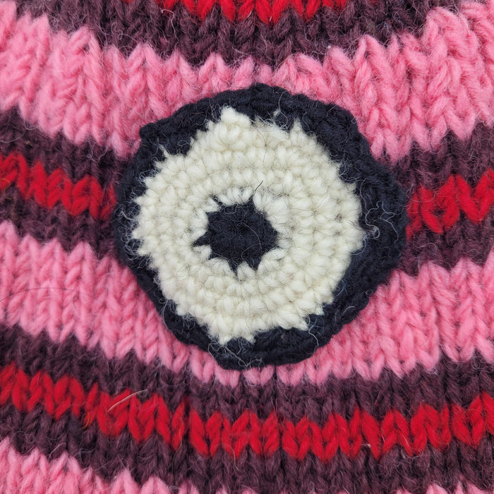 The Window, Milford Haven pink and red striped wool beanie with a circular minion eye detail and fleece lining.