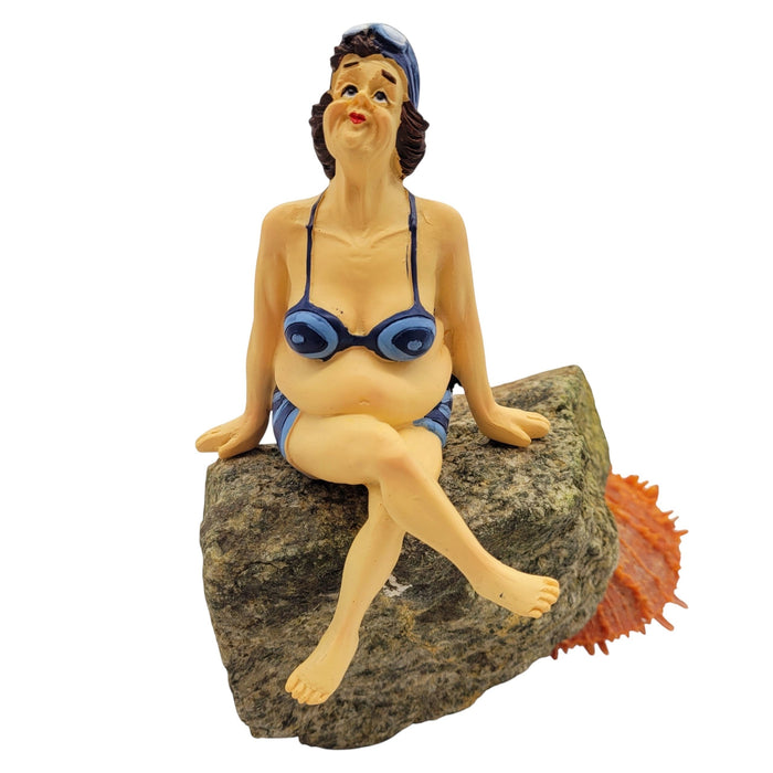 The Window, Milford Haven resin shelf-sitter figurine of a woman in a blue bikini sitting on a rock with crossed legs.