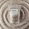 The Window, Milford Haven Starlight Elixir fragranced white candle sand in a 300g pouch surrounded by loose wax beads.