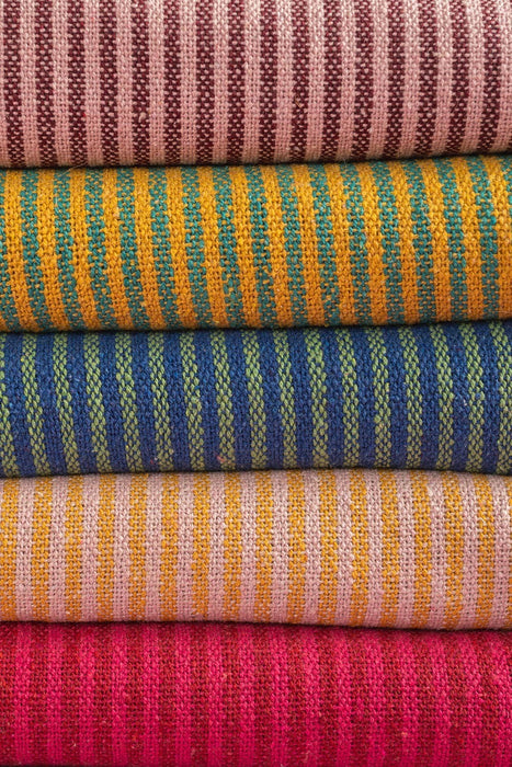 The Window, Milford Haven recycled cotton striped throws in red, pink, yellow, teal, and blue stacked textures.