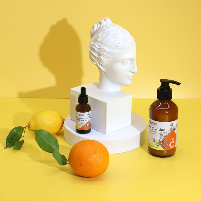 The Window, Milford Haven Vitamin C body lotion and face serum with fresh orange and lemon near a white bust sculpture.