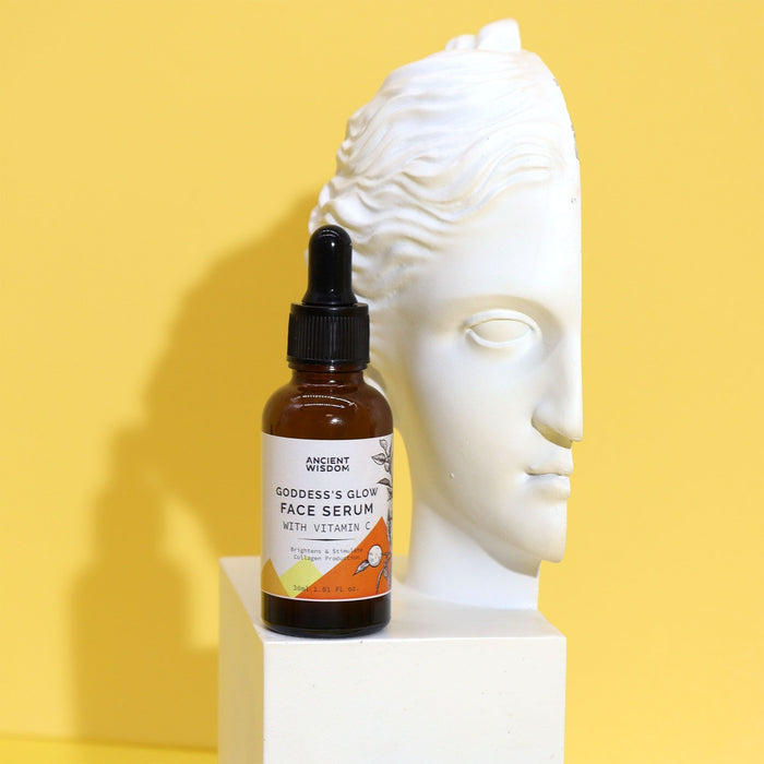 The Window, Milford Haven Goddess’s Glow Vitamin C face serum in an amber glass bottle next to a white bust sculpture.