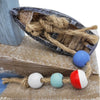 The Window, Milford Haven wooden coastal ornament featuring a miniature boat with rope and colorful fishing floats