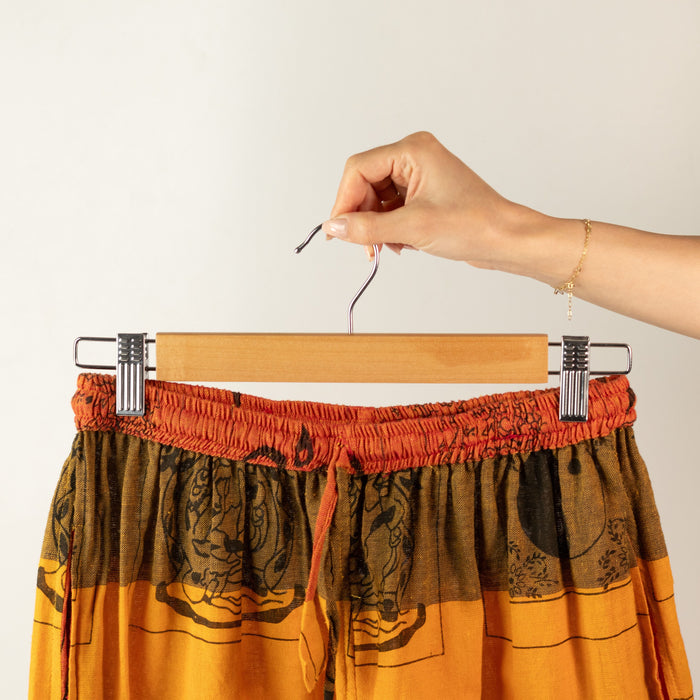 The Window, Milford Haven wooden clip hanger holding orange patterned trousers with adjustable metal clips