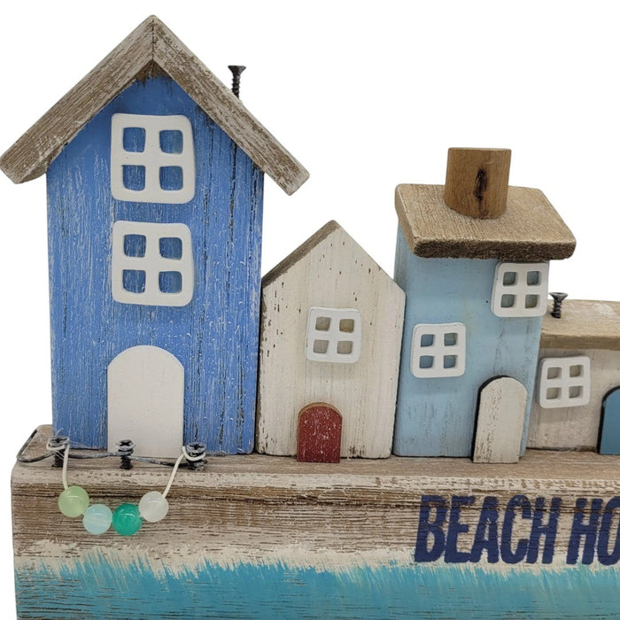 The Window, Milford Haven wooden coastal scene featuring a row of blue and white beach houses with rustic finish.