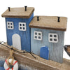 The Window, Milford Haven wooden coastal ornament featuring two blue cottages, a lifebuoy, and rustic seaside details.
