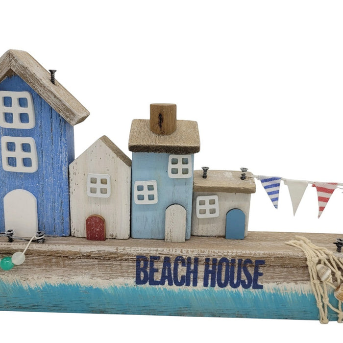 The Window, Milford Haven wooden coastal scene featuring miniature blue and white beach houses with bunting.