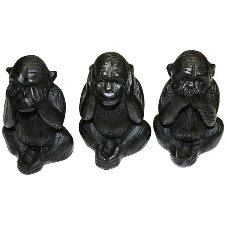 Three wise black wooden carved monkeys figurines showing see no evil hear no evil and speak no evil poses