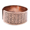 Copper-colored metal cuff bracelet with an intricate engraved flower of life pattern called tibetan mantra bracelet
