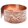 Copper wide cuff bracelet featuring an engraved reclining figure with swirling patterns in tibetan mantra design