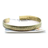 A narrow brass cuff bracelet with a textured tribal leaf pattern featuring tibetan mantra design details