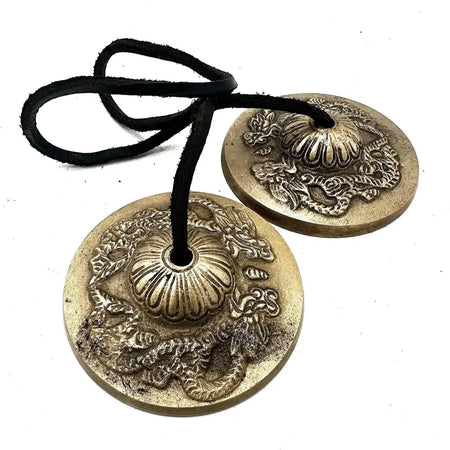 Pair of brass tibetan tingsha cymbals with dragon and floral embossing hanging on black leather cord