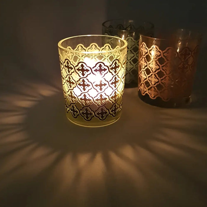 A translucent amber glass tealight holder with a tiled pattern and gold-toned metallic detailing