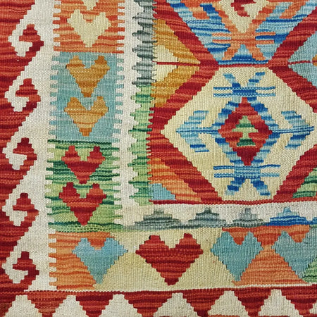 Traditional afghan flat-weave kilim rug with bold red blue orange and green geometric patterns on cream wool background