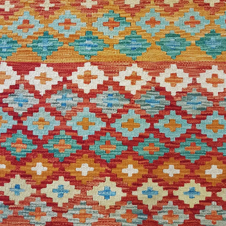 Traditional afghan flat-weave kilim rug with bold red teal orange and cream diamond patterns made of 100% wool