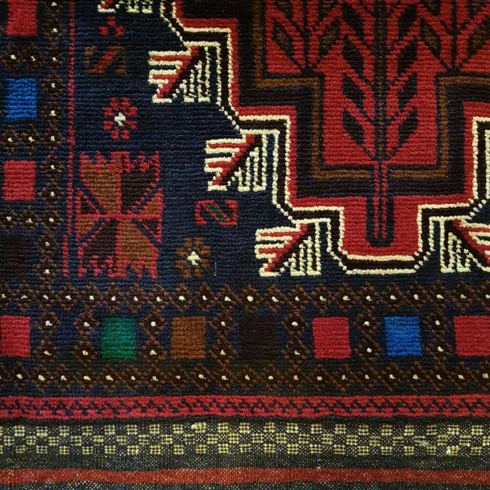 Traditional afghan mushwani rug with geometric and tree motifs in red, navy, brown, green, and cream wool fibers