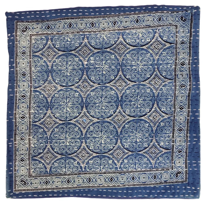 Blue kantha cushion cover with intricate white and black embroidered swirling patterns on a standard cushion