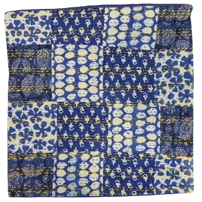 A traditional blue kantha patchwork cushion cover with blue and white fabric squares and yellow stitching seams