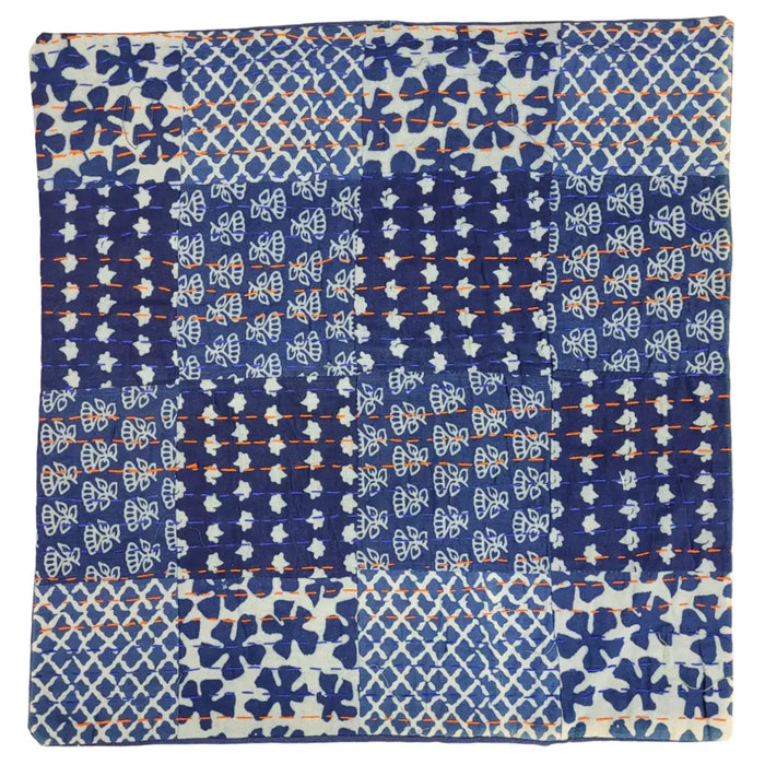 A traditional blue kantha patchwork cushion cover with stitched floral and geometric fabric squares and orange thread details
