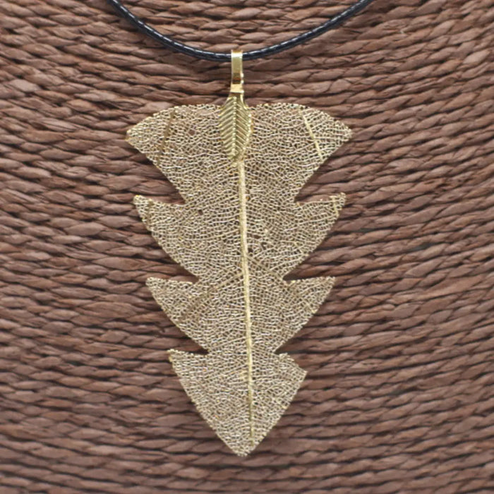 Gold tree leaf necklace with intricate mesh detailing on a leaf pendant hanging from a black cord