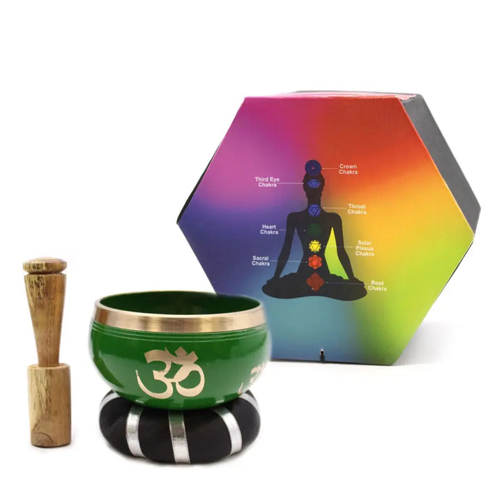 Green tibetan singing bowl with gold rim and om symbol resting on black silver cushion with wooden mallet bowl set