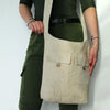 Beige natural linen bag with two front pockets and wooden button closures and an adjustable shoulder strap