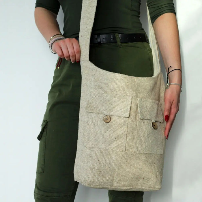 Beige natural linen bag with two front pockets and wooden button closures and an adjustable shoulder strap