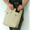 Beige canvas bag with two front pockets secured by wooden buttons and an adjustable natural strap