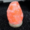 A glowing orange usb himalayan salt lamp with rough natural rock texture and smooth stone base showing hygroscopic properties